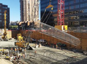 Reinforcing steel cages form the drilled piers used in the foundation for 1144 Fifteenth Street. Due to the length of the piers, the reinforcing steel was built in two sections that were spliced together. Here the second section is hoisted into place.