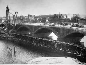 Bridge construction. Concrete hoisting tower (130 feet) shown. Concrete was transported from mixing plant on West Springfield side along a temporary wood trestle 70 feet upstream. Courtesy of the Lyman and Merrie Wood Museum of Springfield History.