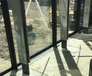 View of the erected steel paired plate mullions and two-bolt connection at the base of the glass wall.