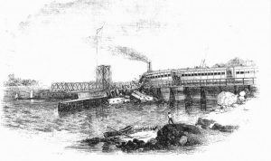 Train in the river with some cars still on approach spans, New York City to the right.