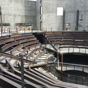 Suspended radius framing for seating with cantilevered tubes at bottom row to allow the slip stage to retract beneath the seats.