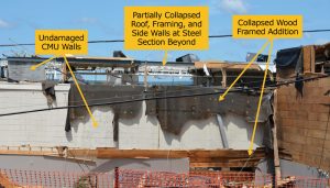 Figure 2. Building D (middle and background) and Building A (foreground) partial collapse of wood and steel framed elements in line with undamaged CMU walls.