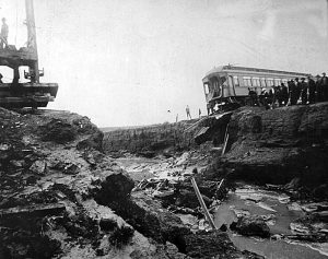 Dry Gulch with Pullman cars on the edge of bank and water subsided.
