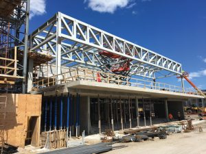 At the podium, a pair of steel roof trusses rest upon and are transferred by a system of cantilevered post-tensioned slabs and beams at Level 2.